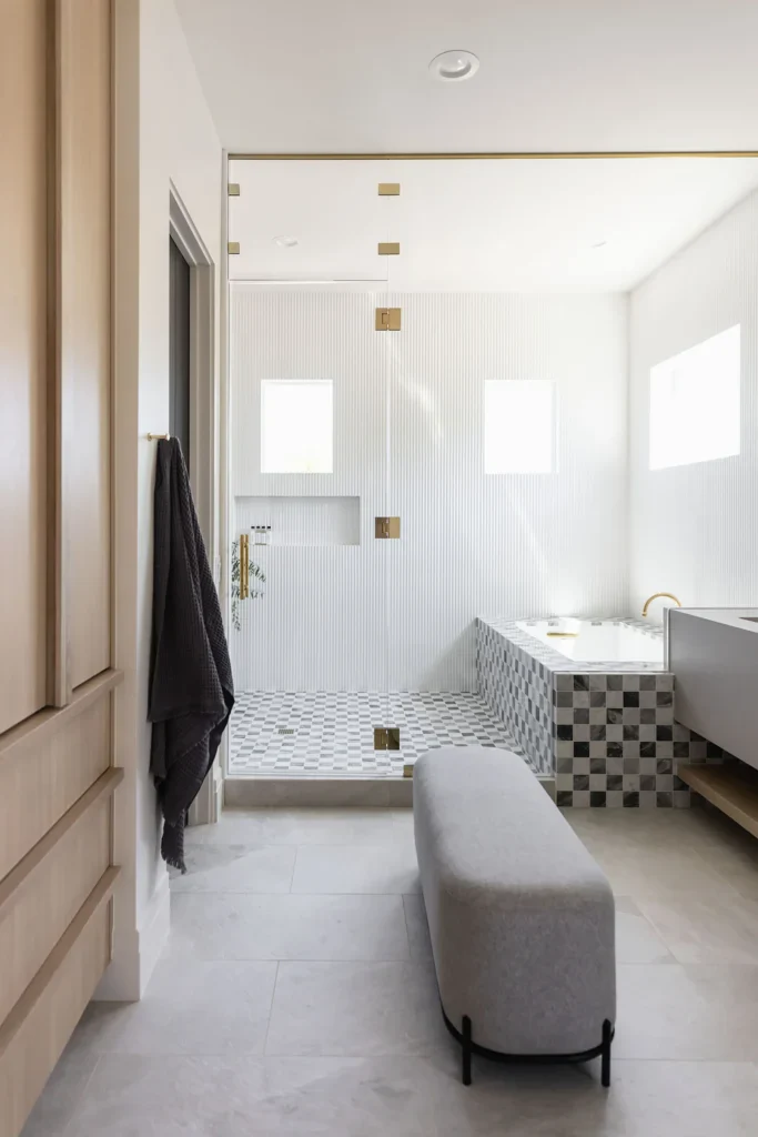 Modern luxury bathroom with glass shower, checkered tub surround, gold fixtures