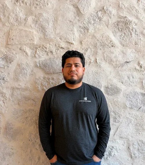 Portrait of Bryan, E&S Builders team member, standing against a stone wall