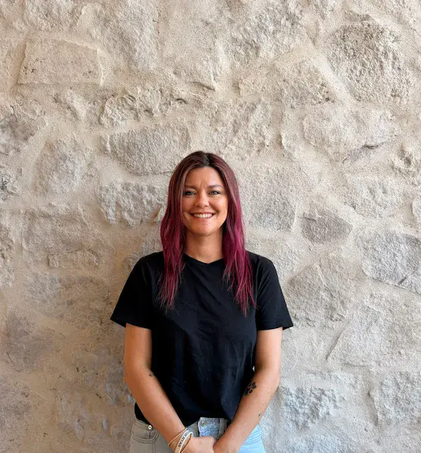 Portrait of Jenny, E&S Builders team member with red hair, standing against a stone wall