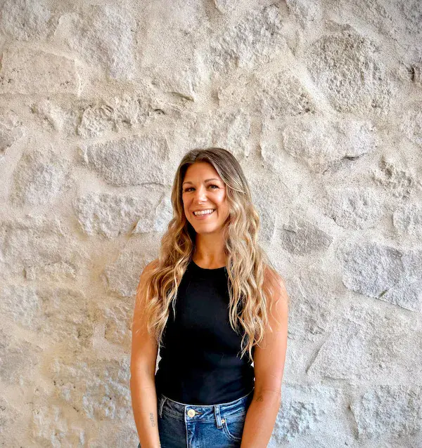 Portrait of Melissa, E&S Builders team member smiling, standing against a stone wall
