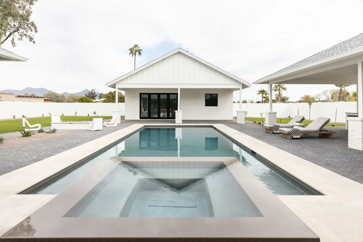 Modern white farmhouse backyard with rectangular swimming pool and spa