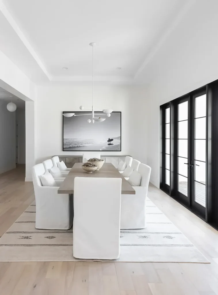 Modern minimalist dining room with white chairs and black French doors