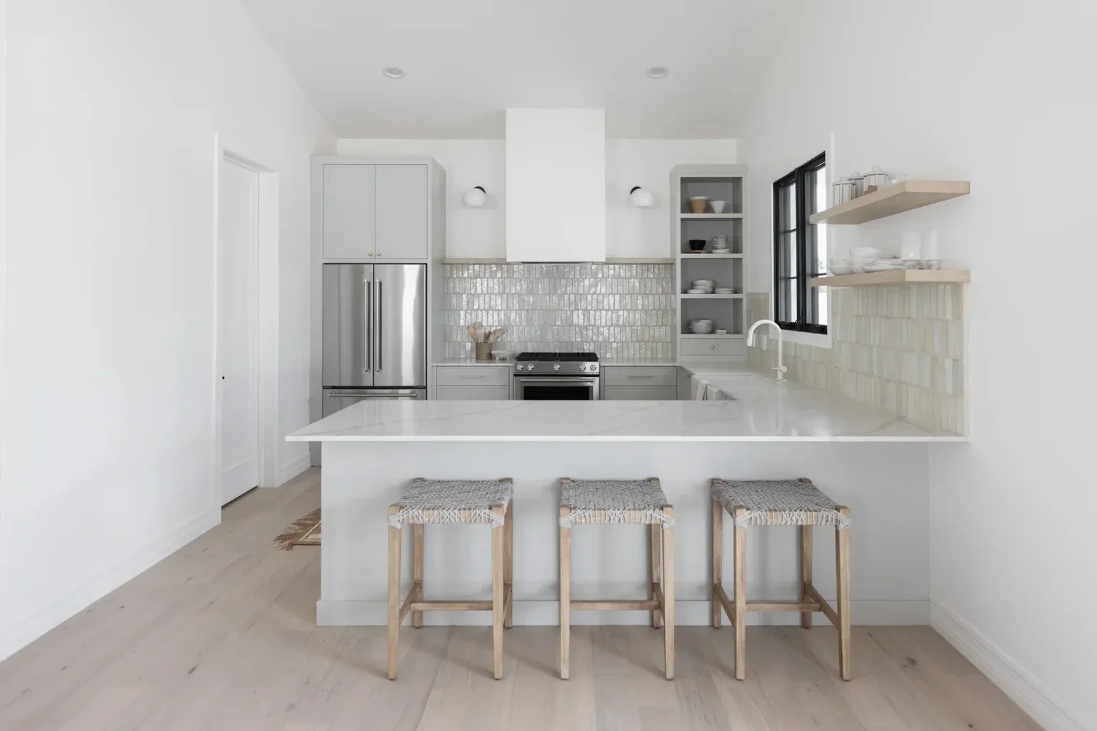 Modern white kitchen with island, woven stools, and tile backsplash