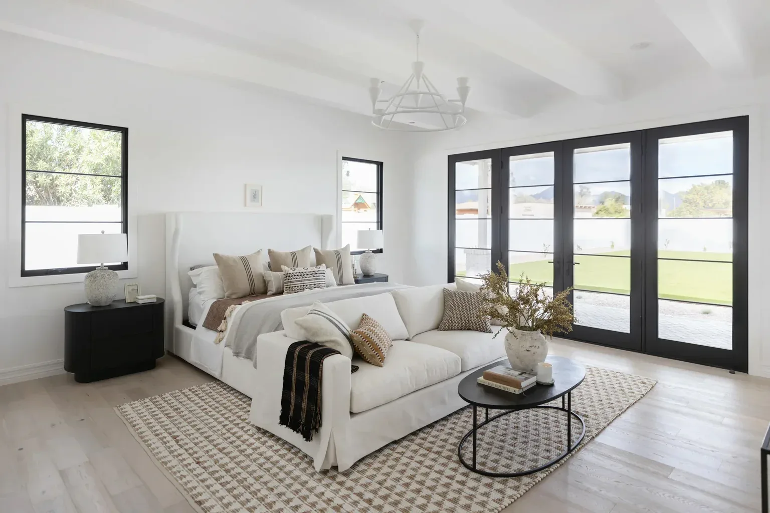 Modern white master bedroom with French doors and neutral decor