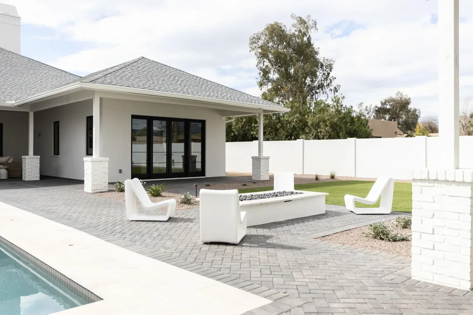 Modern white backyard patio with fire pit and pool