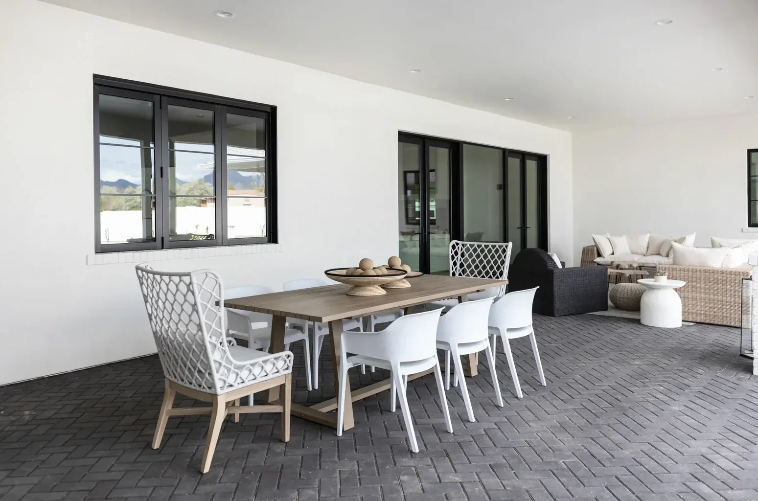 Modern covered patio with wood dining table and white chairs