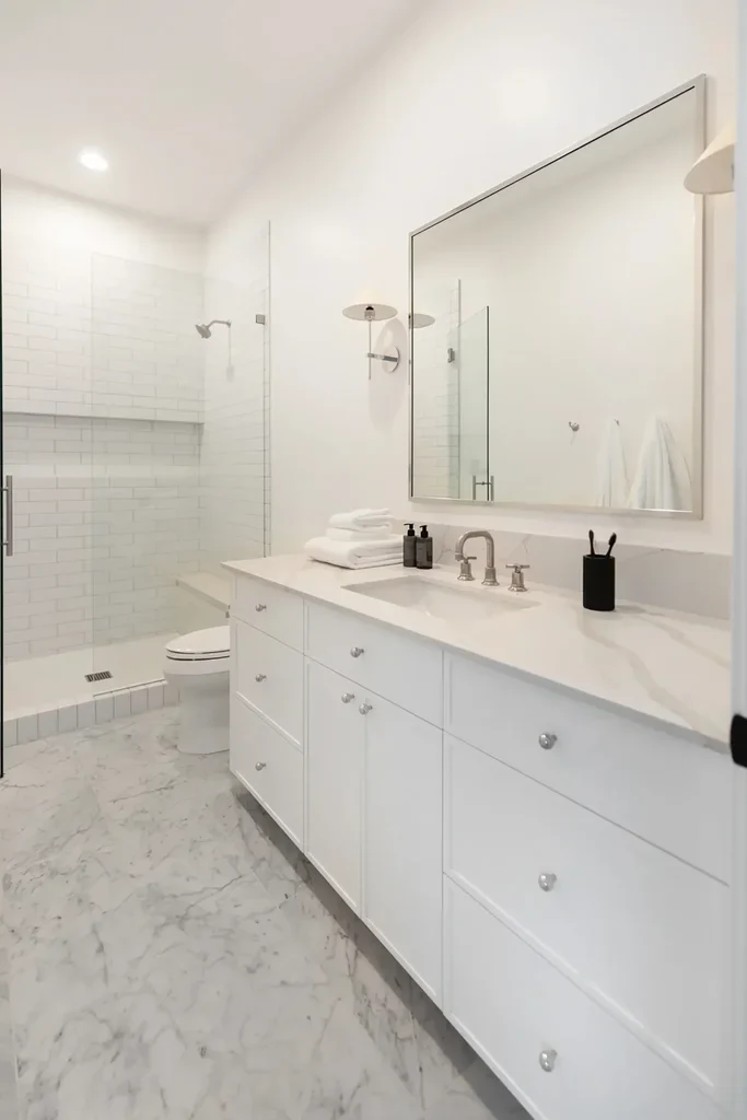 Modern white bathroom with marble floors and glass shower