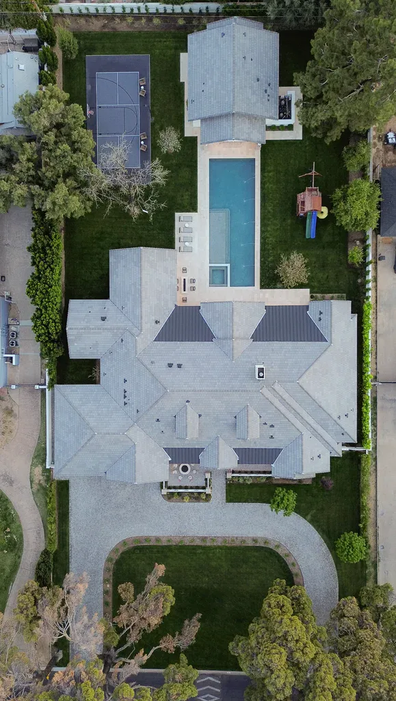 Aerial view of luxury mansion with pool and basketball court