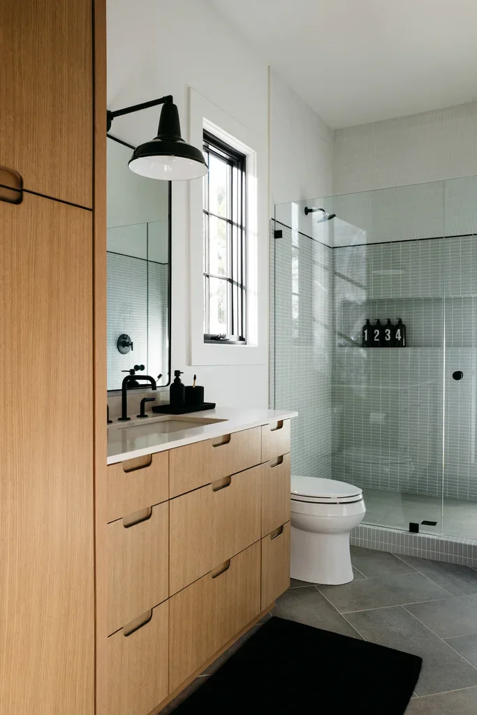 Modern bathroom with wood vanity, glass shower, and black fixtures