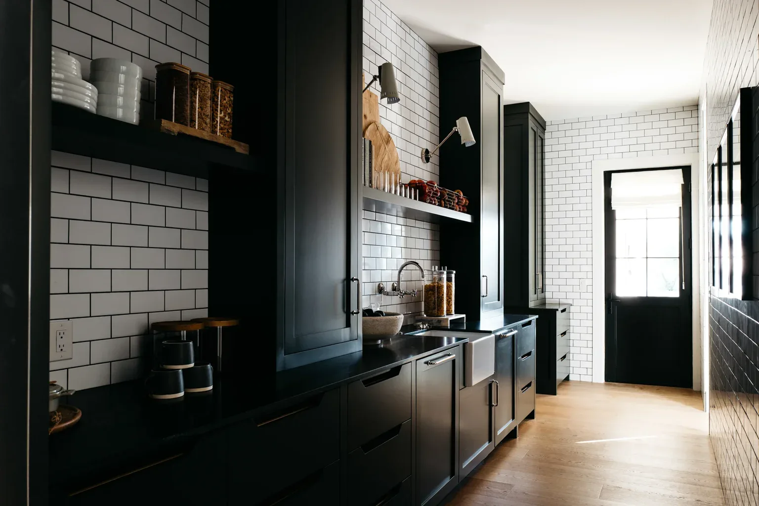 Modern butler's pantry with black cabinets and white subway tiles