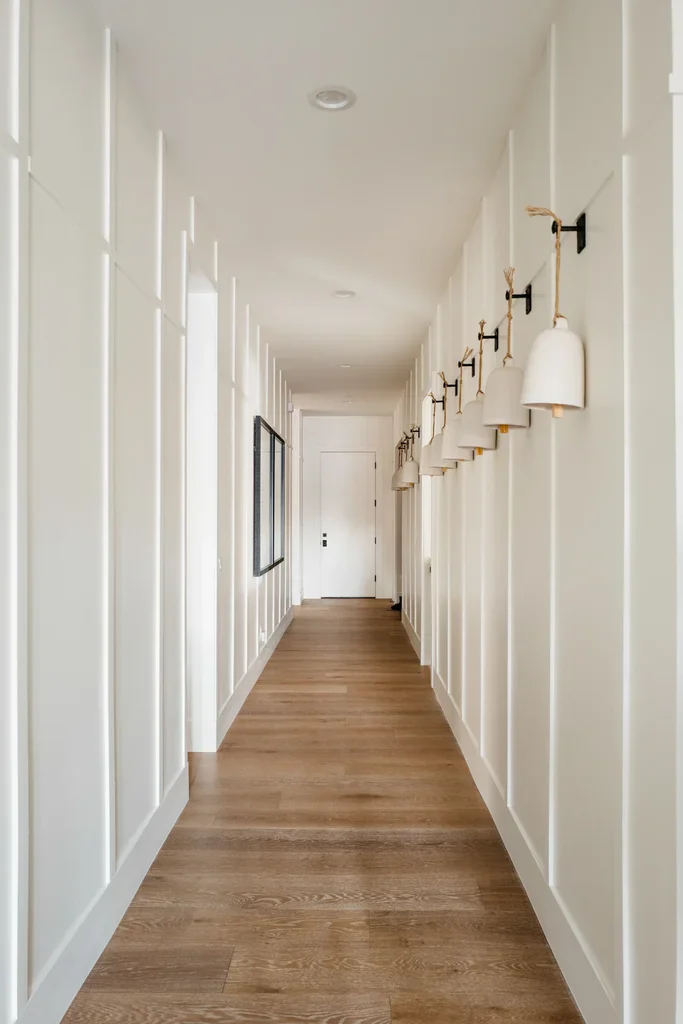 Bright white hallway with wood floors and wall sconces