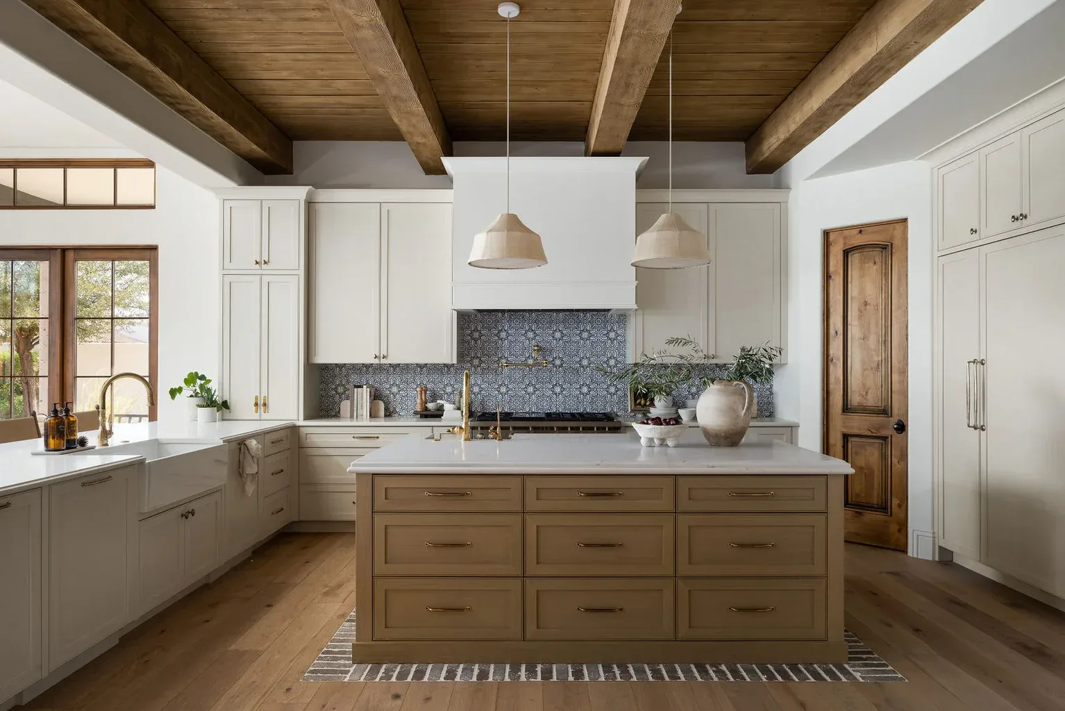 Farmhouse kitchen with wood beams, white cabinets, and blue backsplash