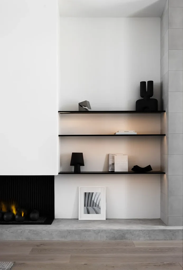 Minimalist white built-in shelves beside modern fireplace
