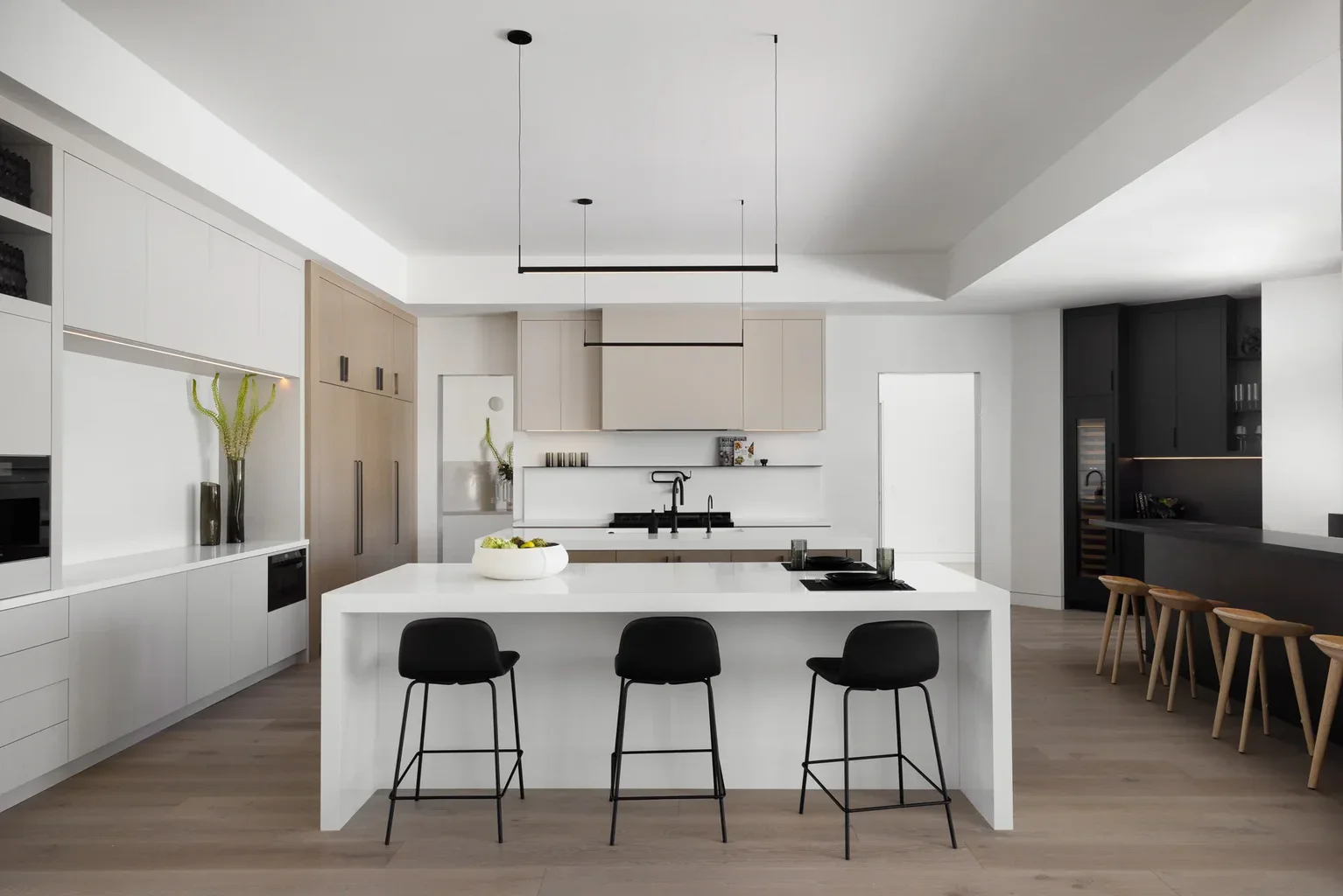 Modern minimalist kitchen with white island and black bar stools