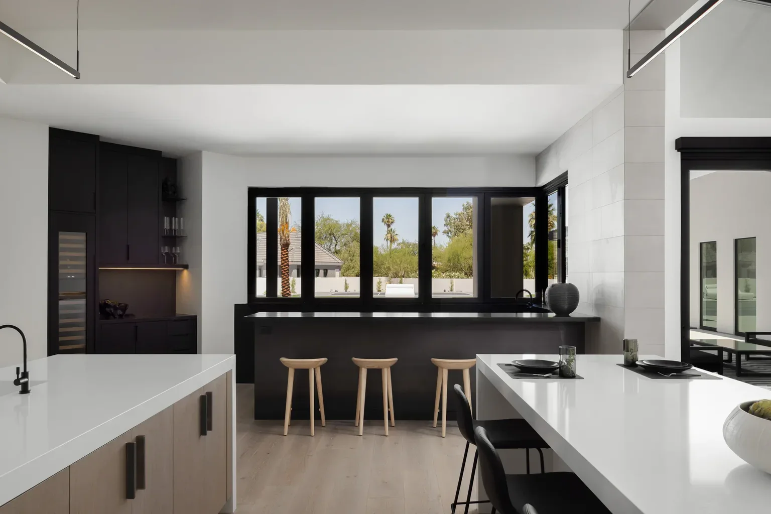 Modern black and white kitchen with bar stools and large windows