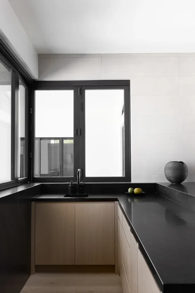 Modern kitchen with black countertops, wood cabinets, and corner windows