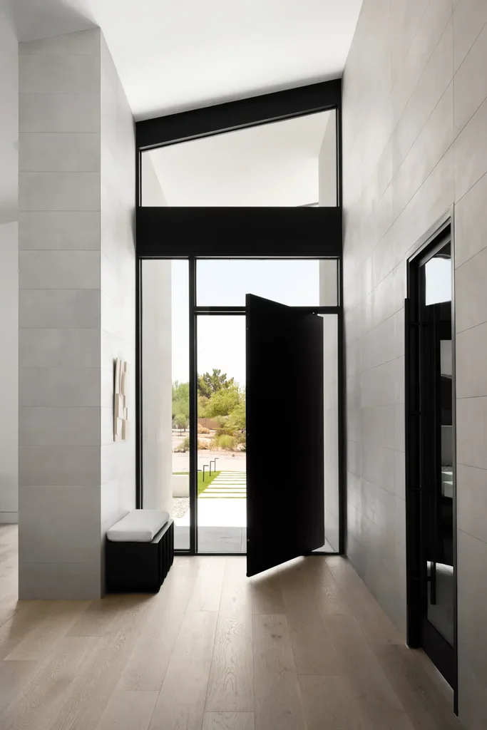 Modern home entryway with black pivot door and floor-to-ceiling windows