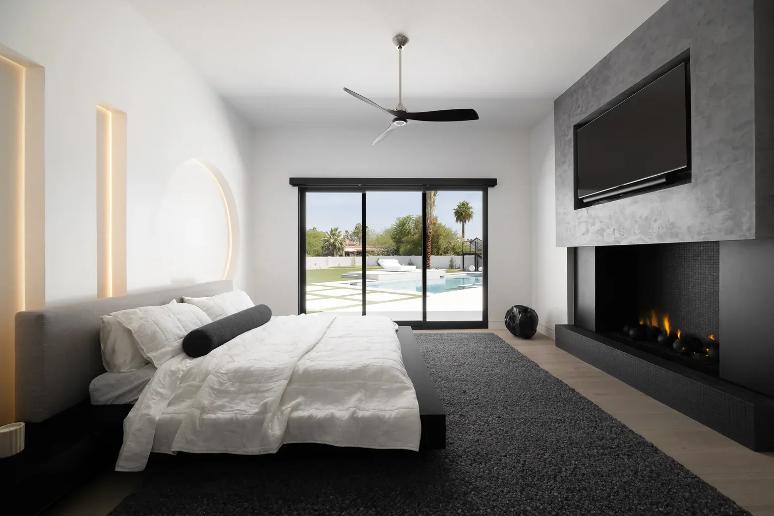 Modern bedroom with fireplace, TV, and pool view