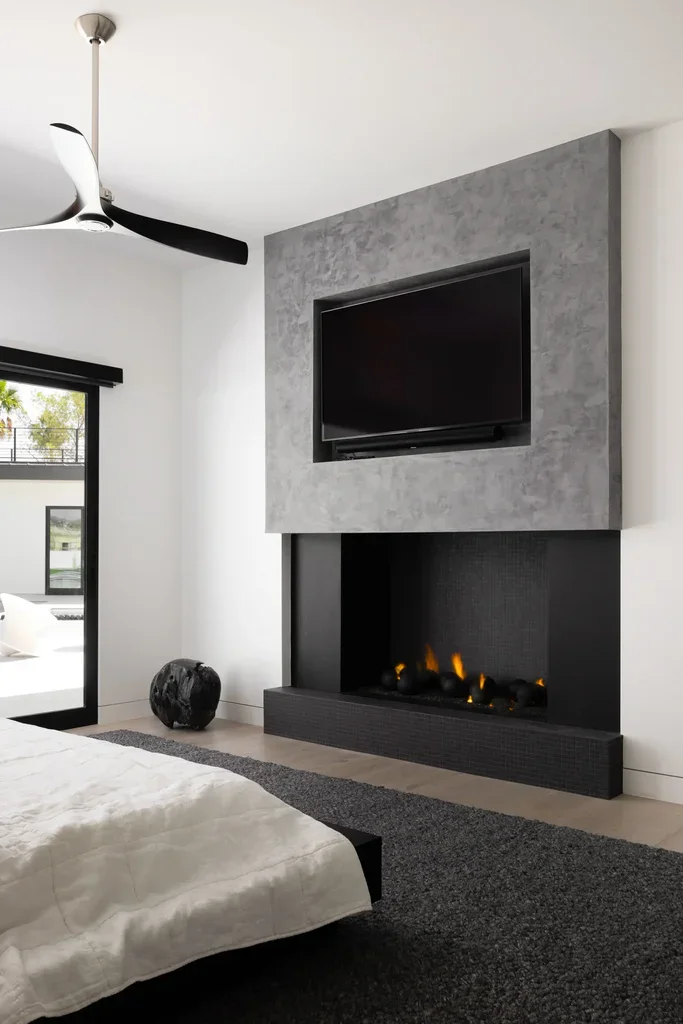 Modern bedroom with fireplace, wall-mounted TV, and ceiling fan