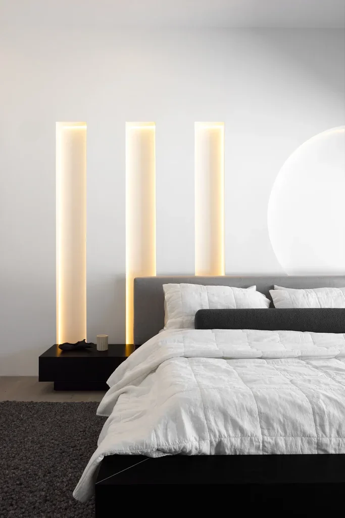 Minimalist bedroom with warm LED wall niches and white bedding