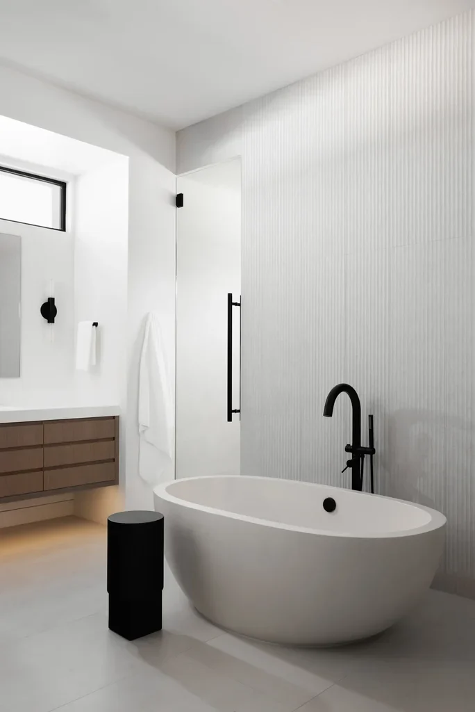 Modern minimalist bathroom with freestanding white tub and black fixtures