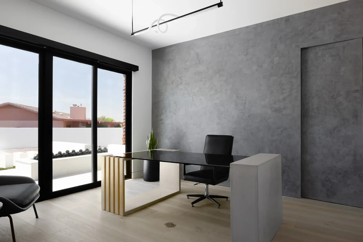 Modern home office with black desk, leather chair, gray textured wall