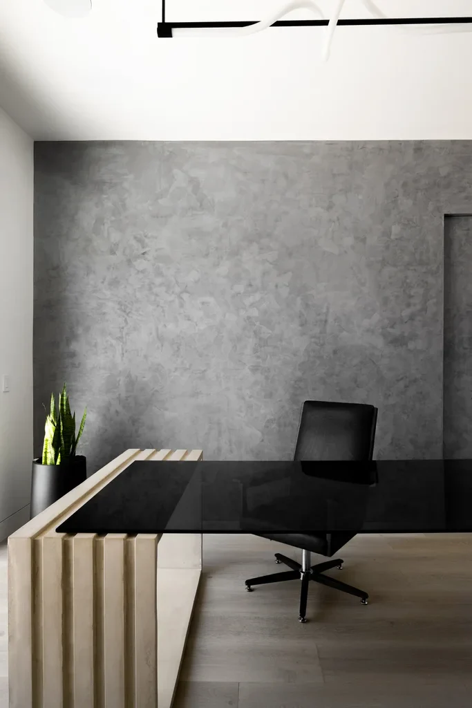 Modern minimalist office with black desk and concrete wall