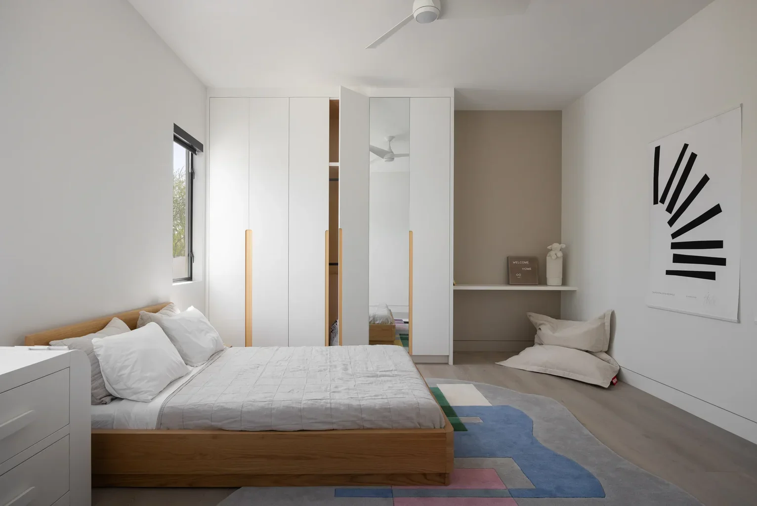 Modern minimalist bedroom with wooden bed and white built-in wardrobes