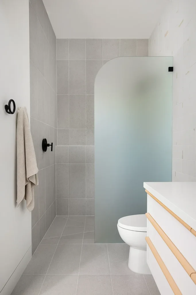 Modern bathroom with frosted glass shower partition and gray tiles
