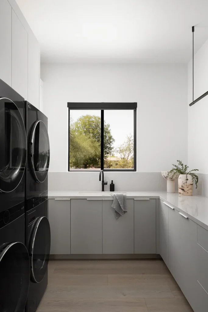 Modern laundry room with stacked washer dryer and gray cabinets