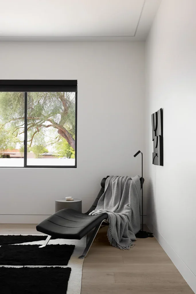 Modern minimalist reading nook with black chaise lounge and window
