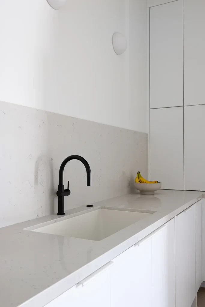 Modern white kitchen with black faucet and marble countertop