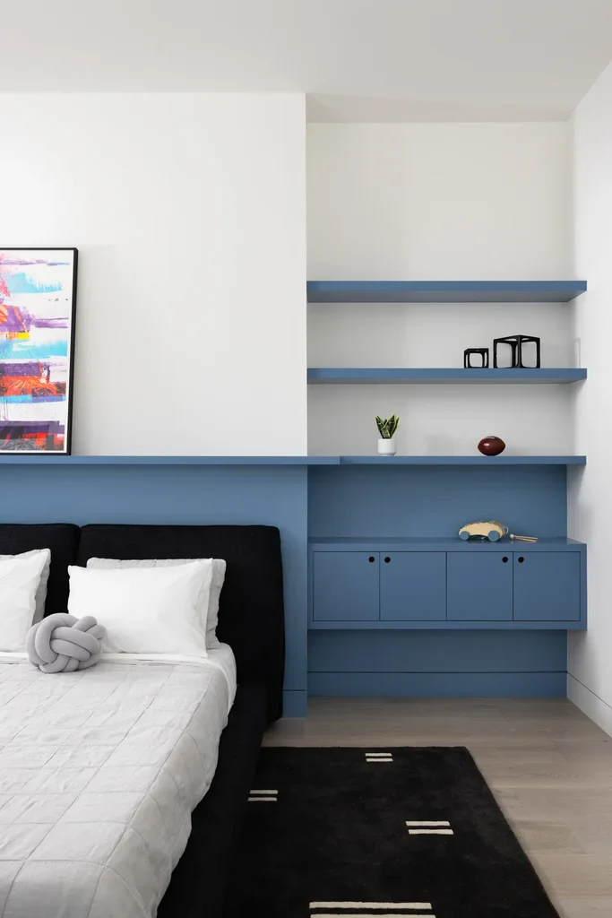 Modern bedroom with blue built-in shelves and black bed