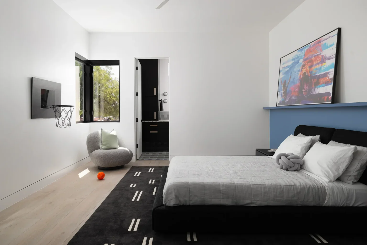 Modern bedroom with basketball hoop, bold artwork, and black bed