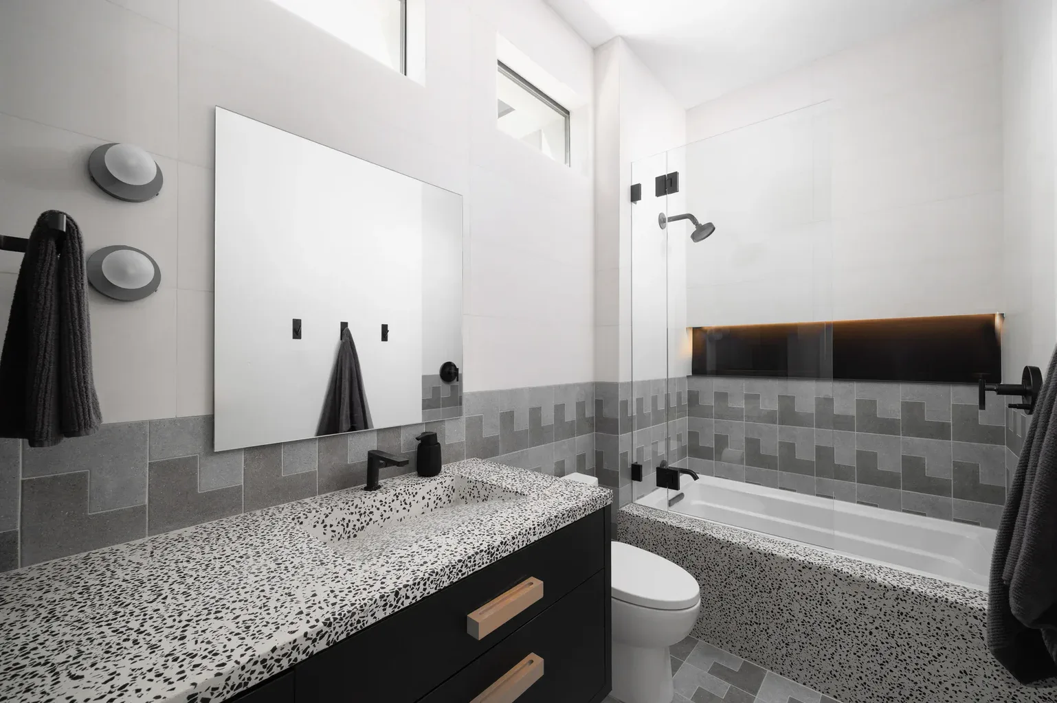Modern bathroom with terrazzo countertop, gray tiles, and bathtub
