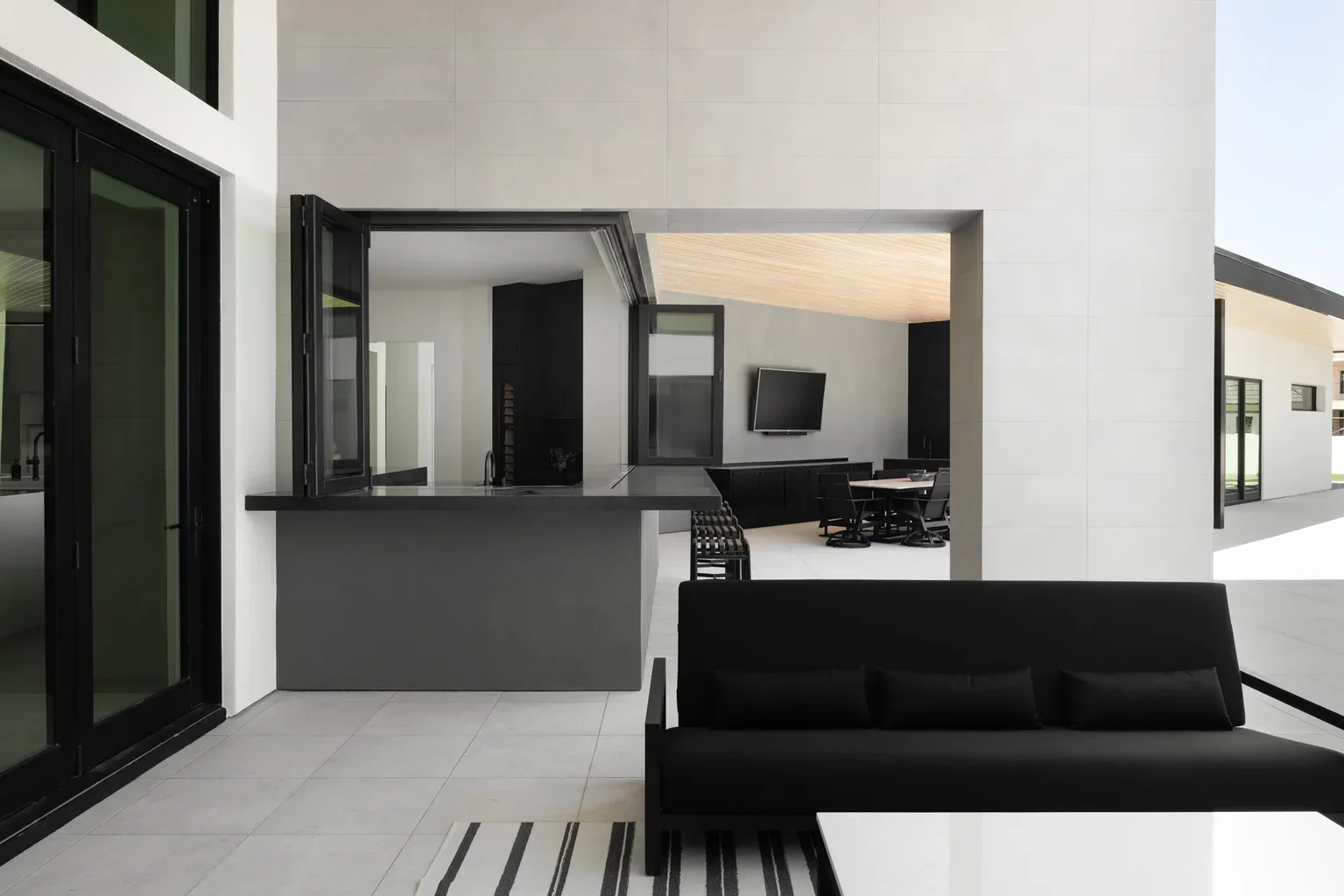 Modern black and white outdoor patio with indoor kitchen view