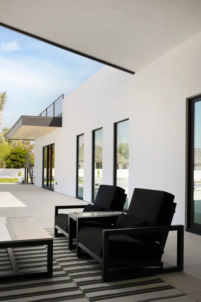 Modern covered patio with black outdoor furniture and white walls