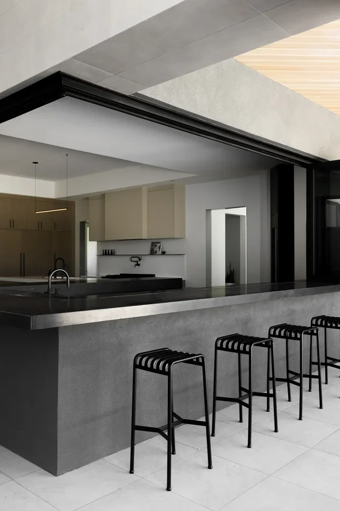 Modern kitchen with concrete island and black bar stools