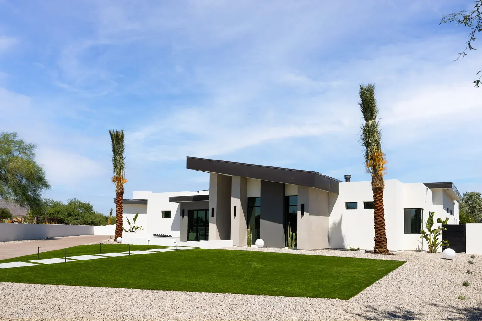 Modern white desert home with palm trees and green lawn