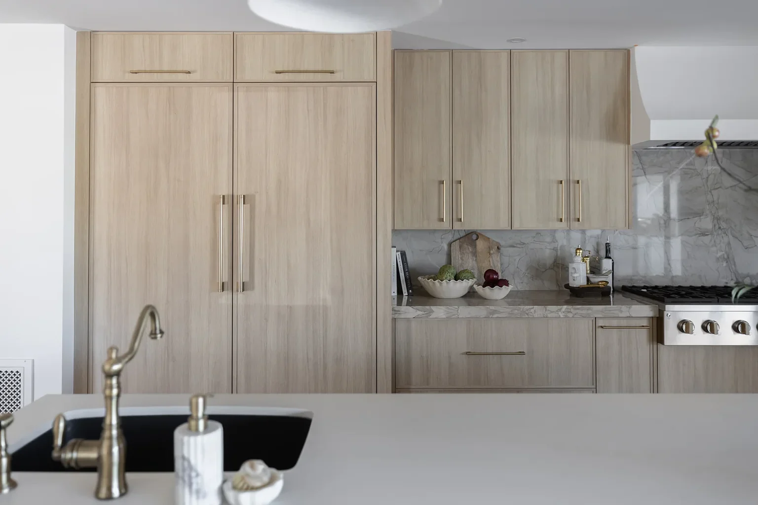 Modern kitchen with light wood cabinets and marble backsplash