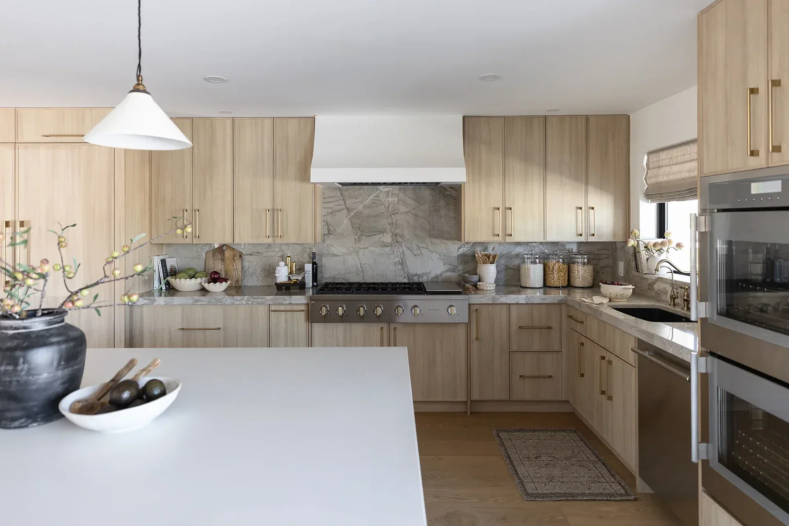 Modern kitchen with light wood cabinets and marble backsplash