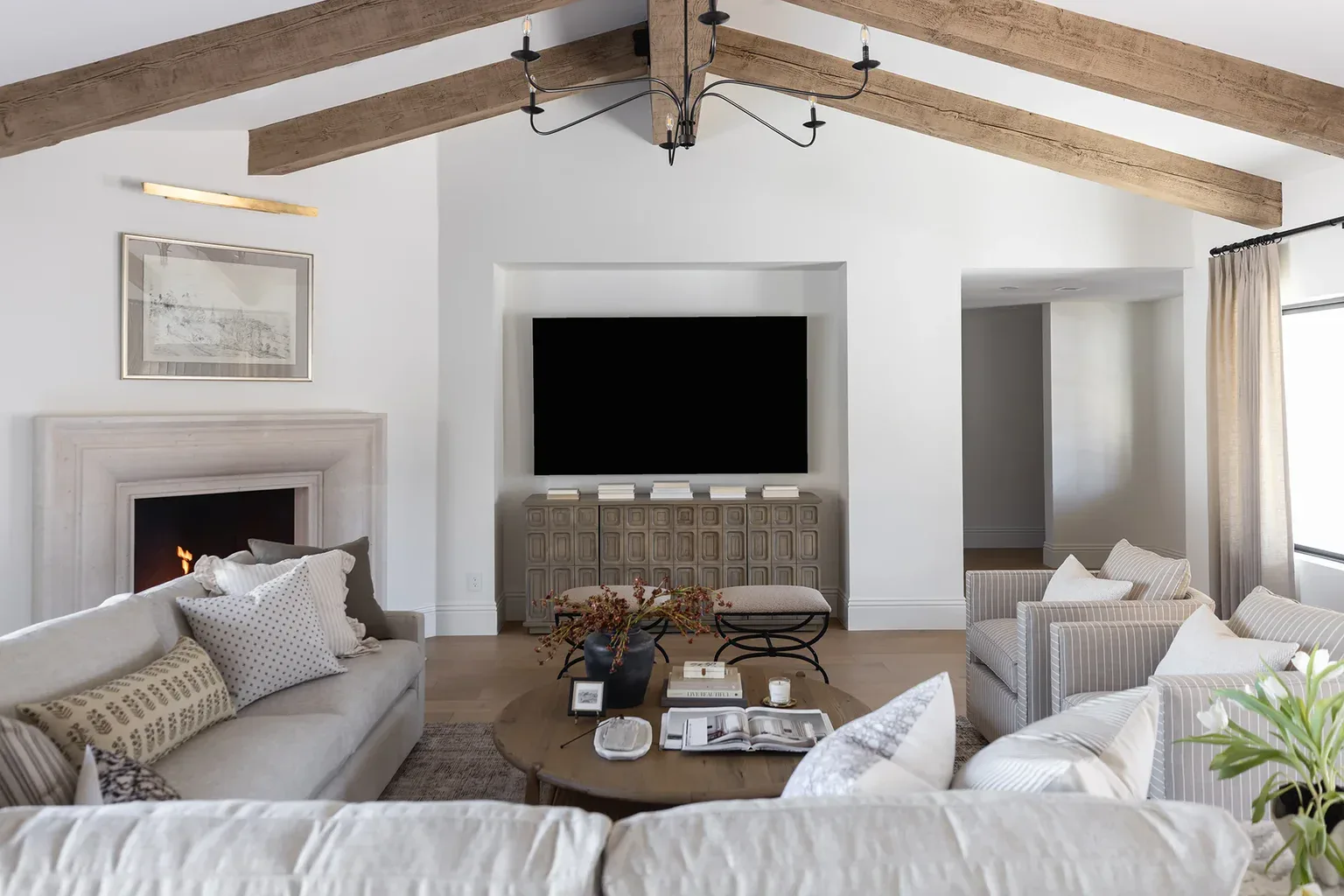 Elegant living room with vaulted ceiling, wood beams, and fireplace