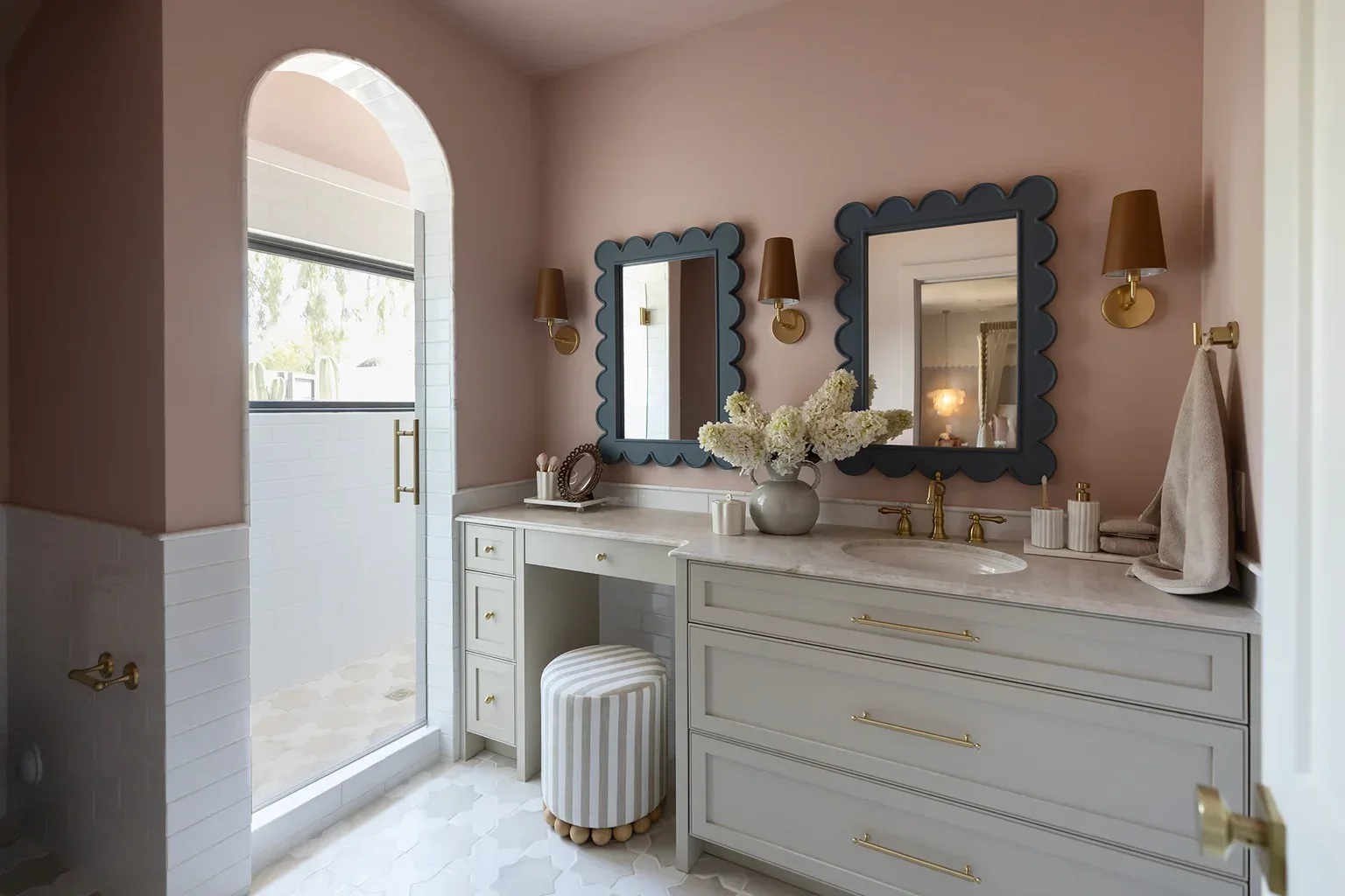 Elegant pink bathroom with scalloped mirrors and gold accents