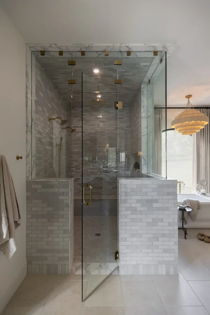 Elegant glass shower with marble tiles and gold hardware