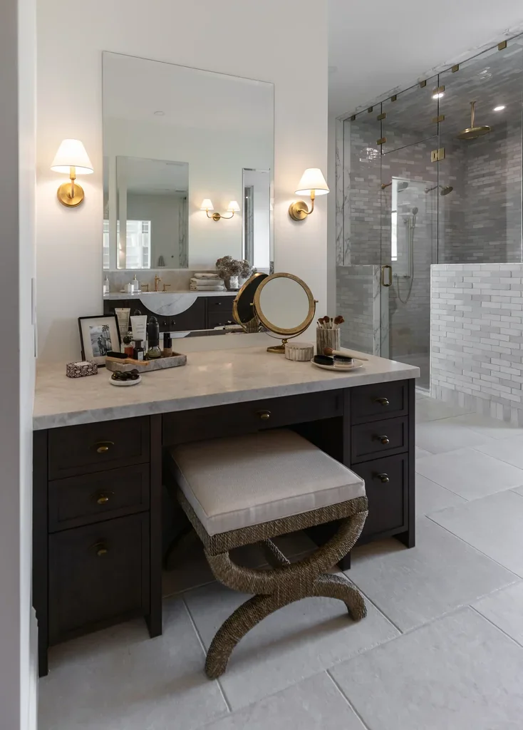 Elegant bathroom vanity with gold sconces and glass shower