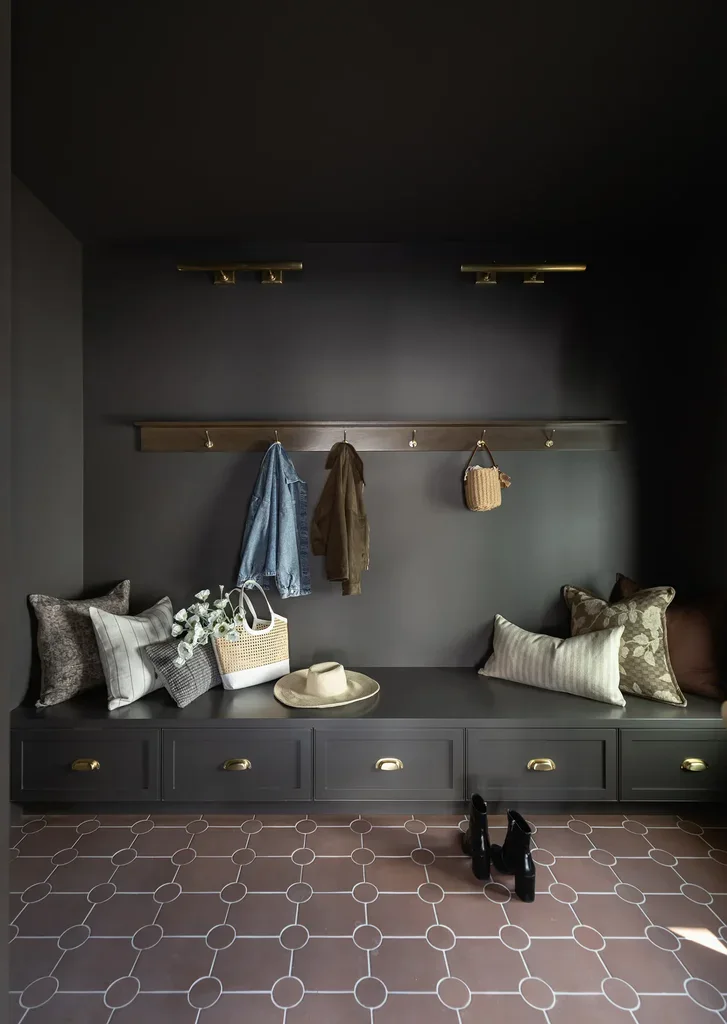 Dark mudroom with built-in bench, hooks, and patterned tile floor