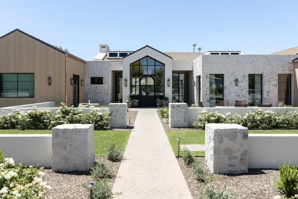 Modern stone resort entrance with manicured garden and pathway