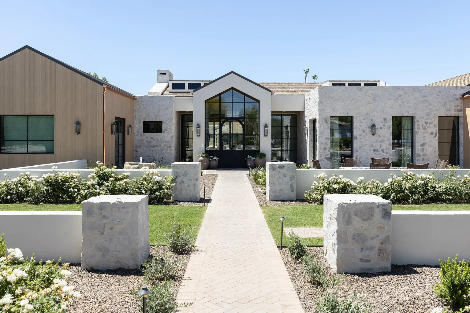 Modern stone resort entrance with manicured garden and pathway